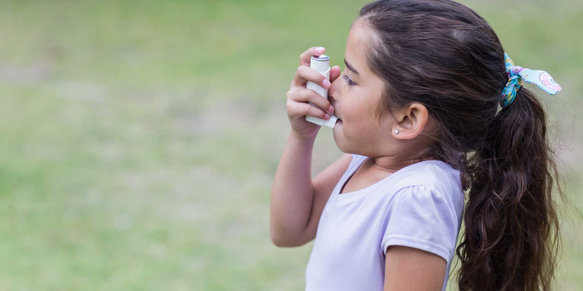 Ein Mädchen mit Asthmaspray in der Hand, bereit zur Nutzung im Freien.